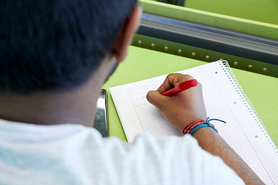 Ein Student sitzt mit einem Notizblock im Hörsaal