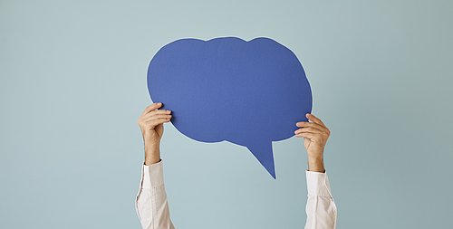 Zwei Hände halten eine Sprechblase hoch